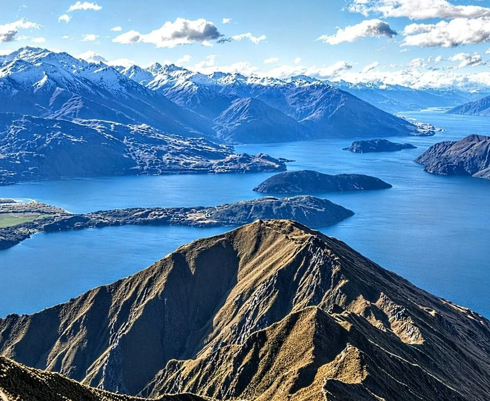 Lake Wānaka and snow-capped mountains seen from a ridge