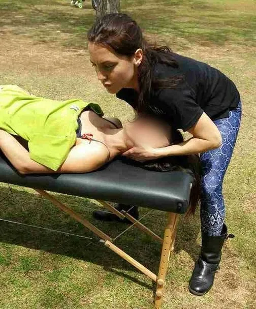 Osteopath supporting a patient's head and neck on a portable table outdoors