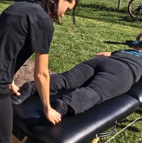 Osteopath working on a patient's legs on a treatment table outdoors