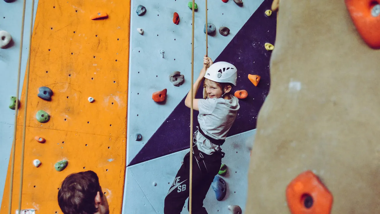 Boy in a helmet climbing an indoor climbing wall
